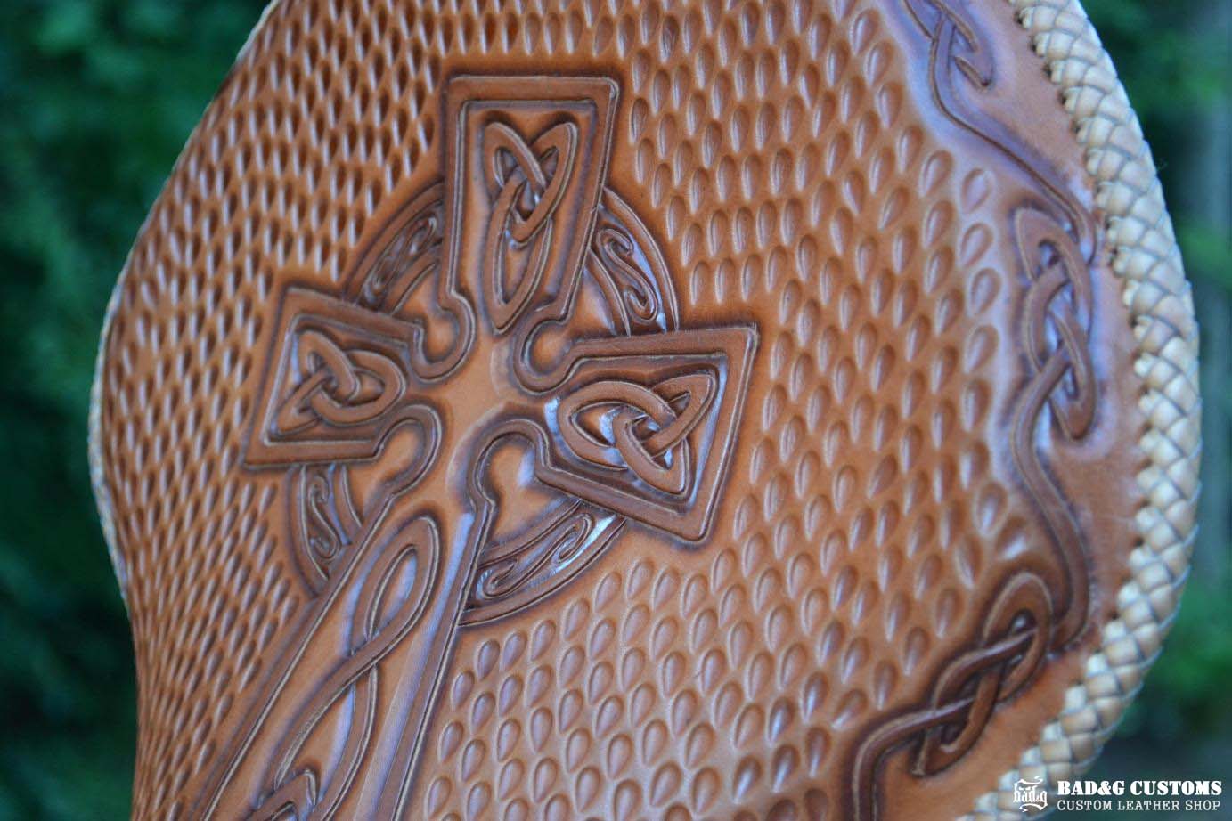 "CROSS" design hand tooled and braided on a chopper solo seat. Brown Veg tan leather with kangaroo lace.