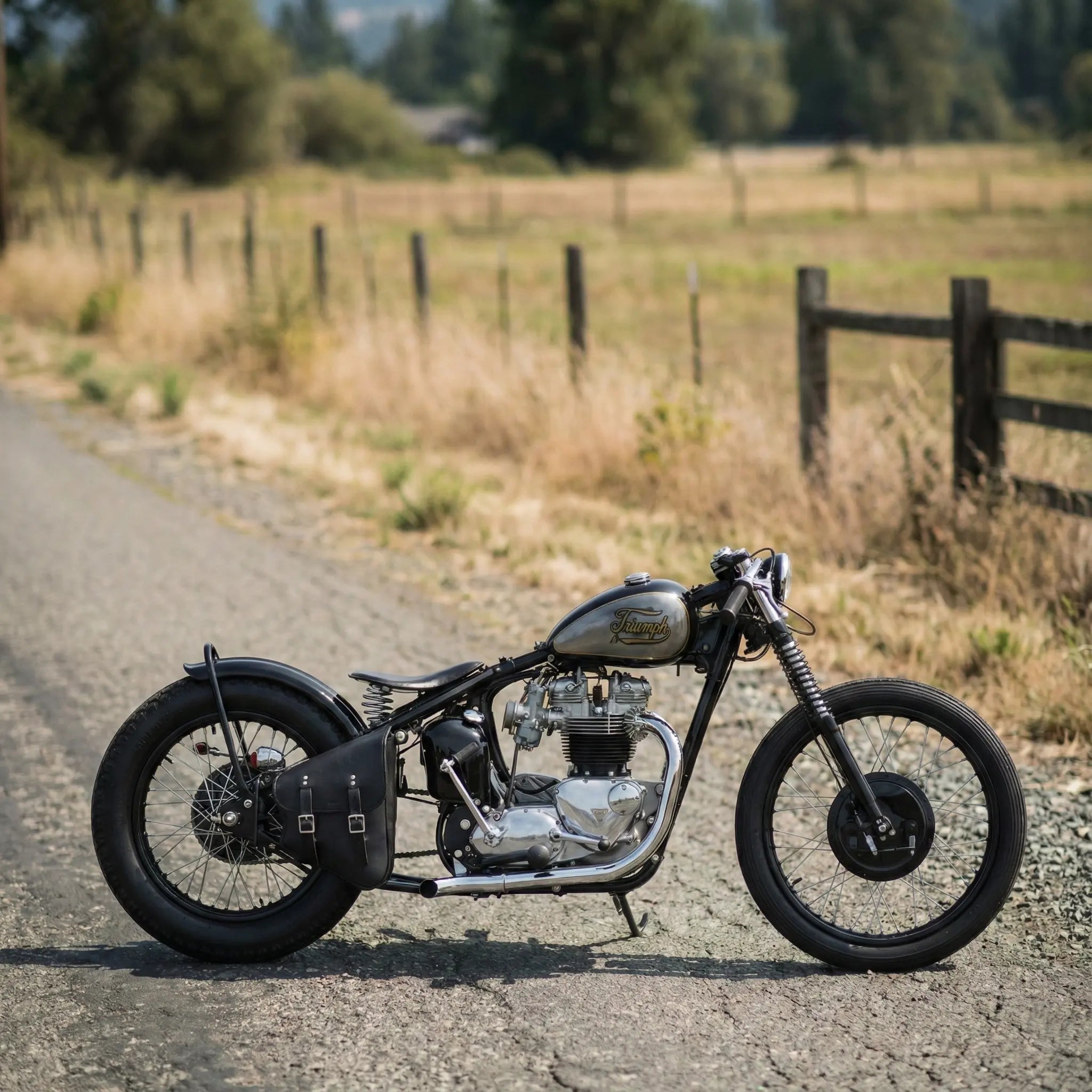 Custom motorcycle on a rural road with a wooden fence and fields in the background