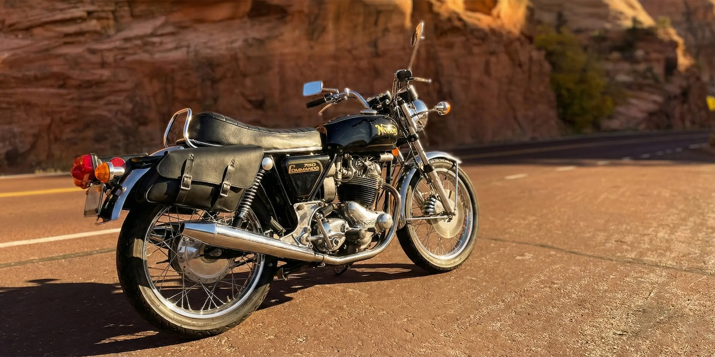 Motorcycle parked on a desert road with rocky cliffs in the background